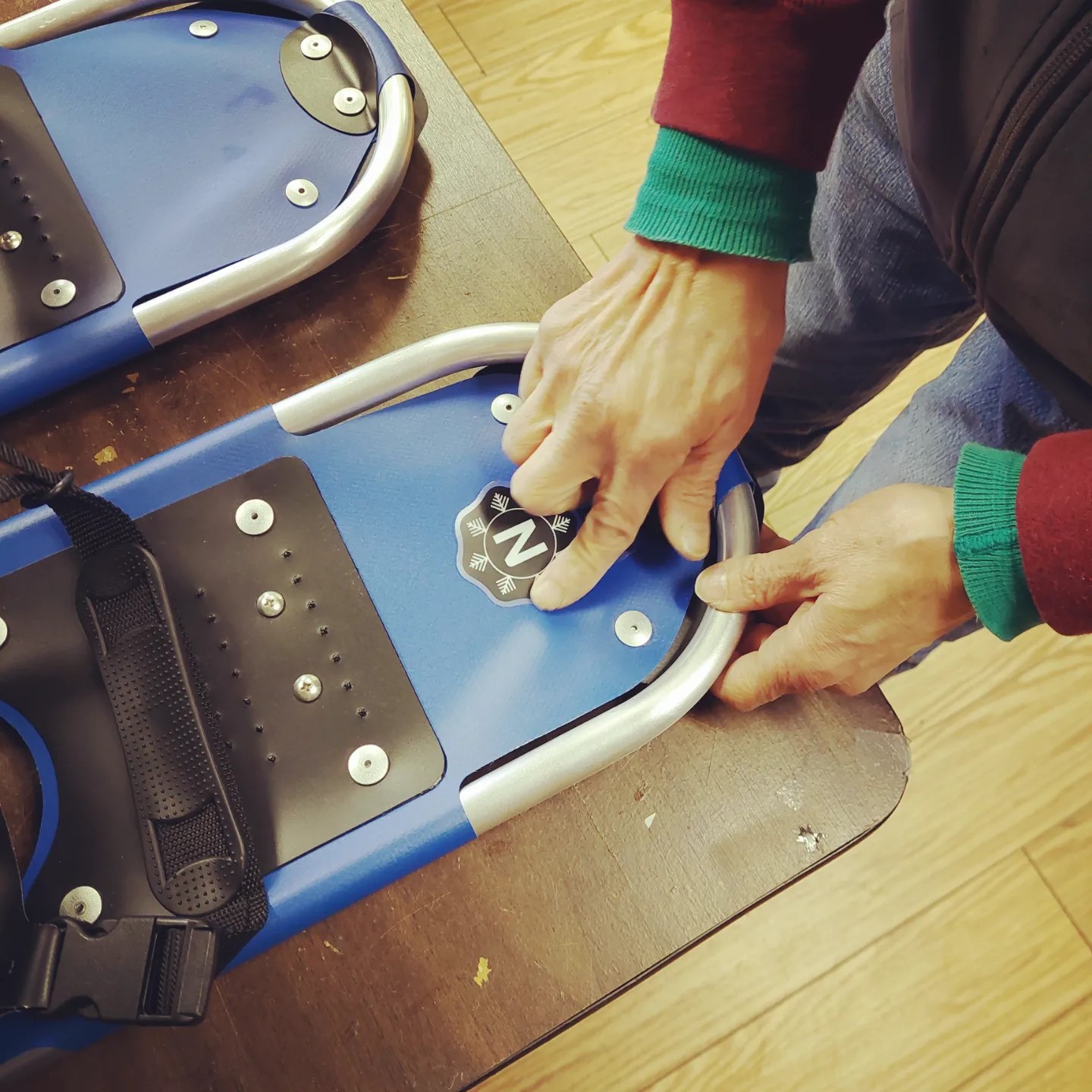 hand adding a logo to blue snowshoes