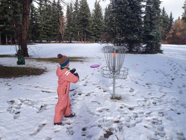 outdoor winter activities ideas: child playing disc golf in winter