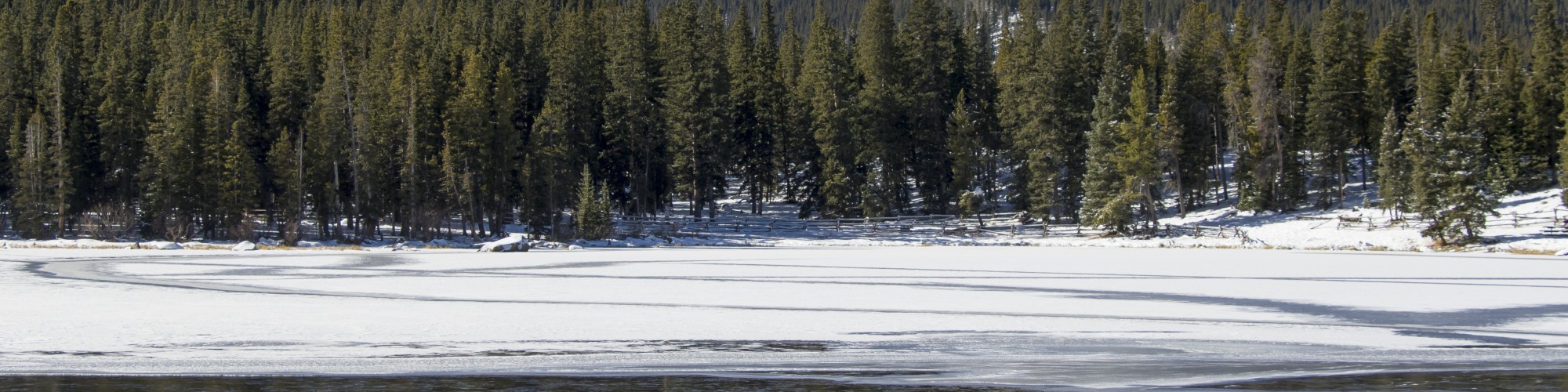 lake with ice and mountains in trees in background