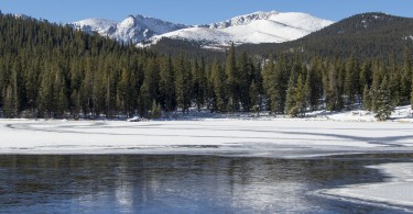 lake with ice and mountains in trees in background