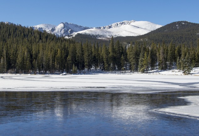 lake with ice and mountains in trees in background