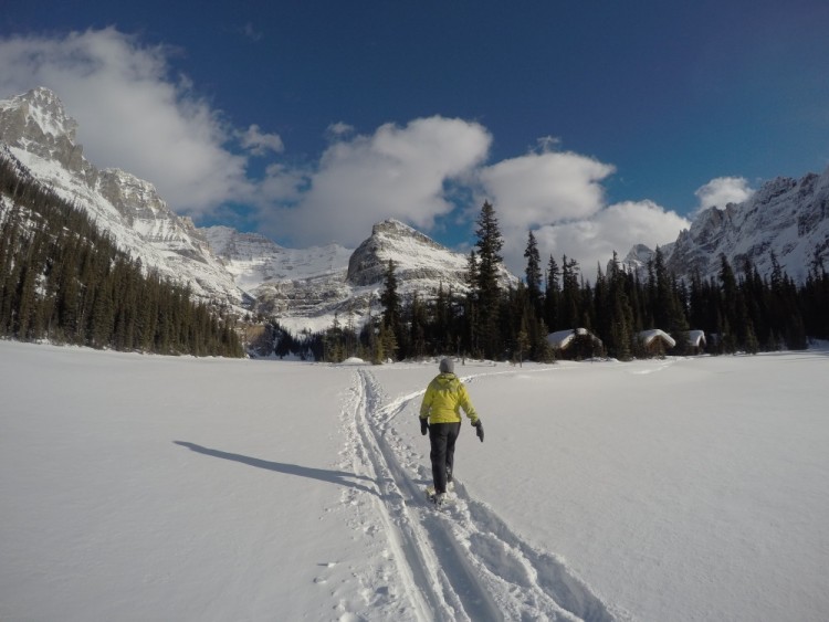 person snowshoeing at Lake O'Hara with cabins and mountains in background