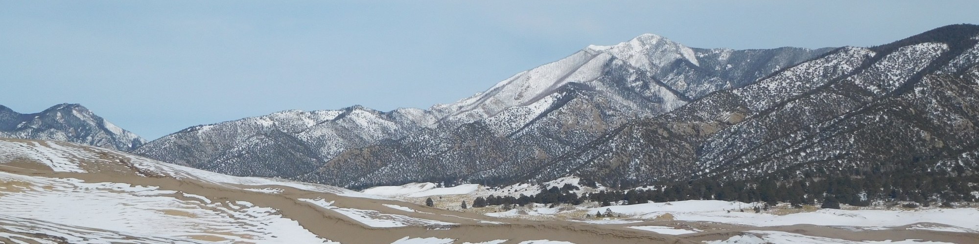 sand and snow at Great Dunes National Park with mountains in background