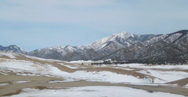 sand and snow at Great Dunes National Park with mountains in background