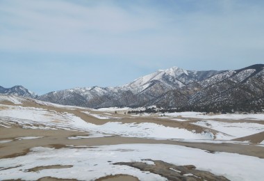 sand and snow at Great Dunes National Park with mountains in background