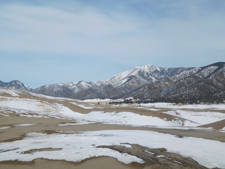 sand and snow at Great Dunes National Park with mountains in background