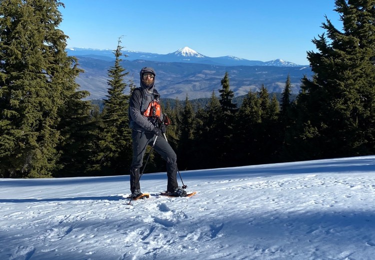 guide standing in the snow with mountains in the background and trees around