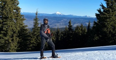 guide standing in the snow with mountains in the background and trees around