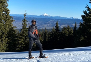 guide standing in the snow with mountains in the background and trees around