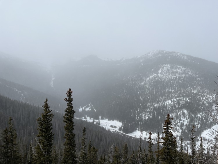 view from above of a valley covered in snow with clouds above