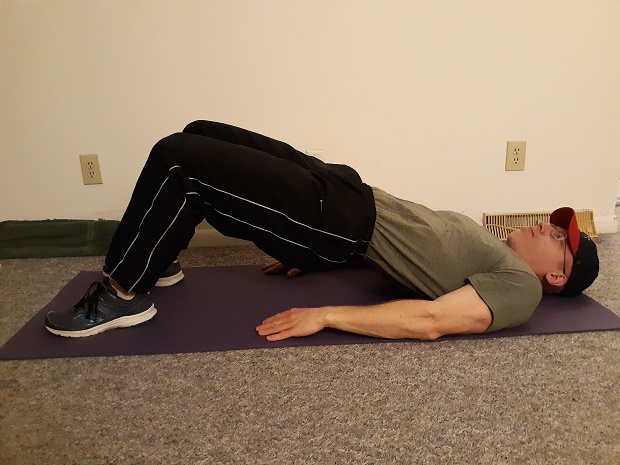 man lying on the ground demonstrating hip bridge exercise