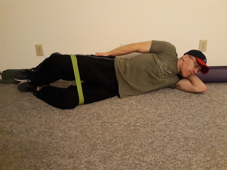 at home hip exercises: man lying on ground demonstrating clamshell exercise