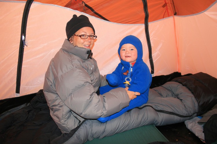 mom and son sitting in tent while winter camping