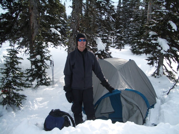 man standing in snow with tent
