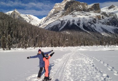 Woman and child standing in snow in front of mountain.