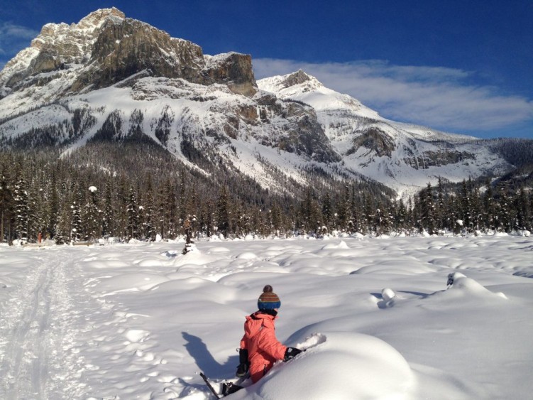 hiking with kids: child sitting in snow pile.