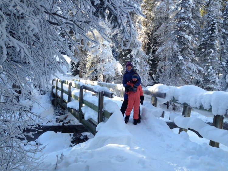 hiking with kids: adult and child standing on snow-covered bridge