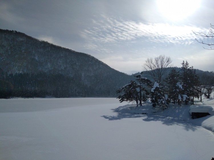 snowy lake near Nozawa Onsen with sun shining in background