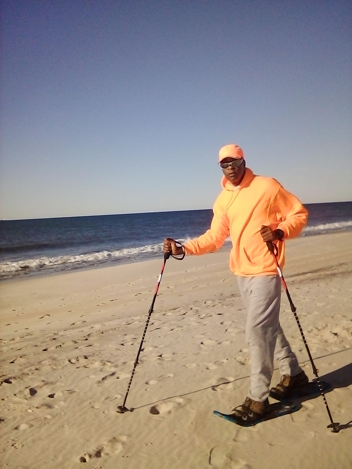snowshoes on sand for fitness: man on beach wearing snowshoes and using poles
