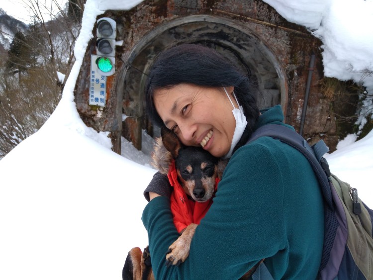 woman and dog near snowy tunnel and streetlight