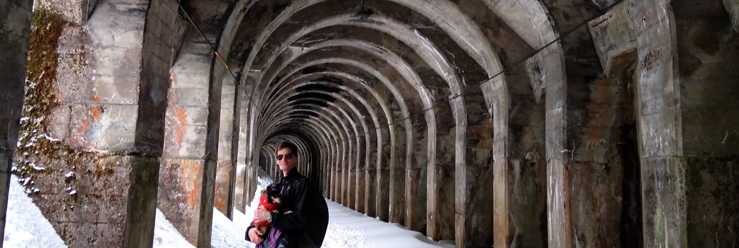 man posing with a dog on snowshoes in snow-filled tunnel