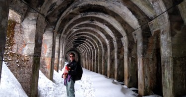 man posing with a dog on snowshoes in snow-filled tunnel