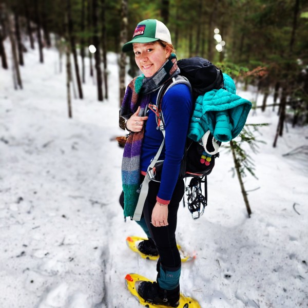 person looking back at camera with backpack and snowshoes