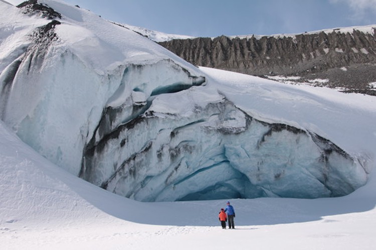 Two people standing in front of an ice cave.