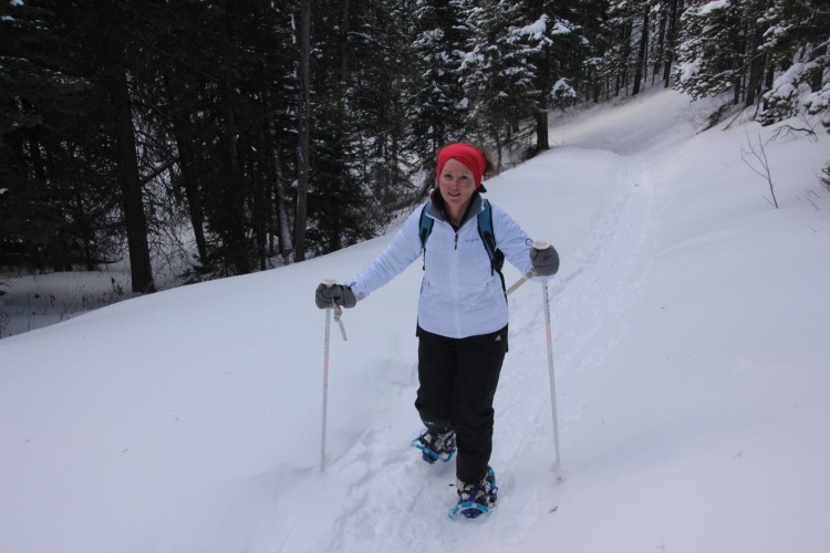 woman wearing mid layer jacket with snowshoes and poles