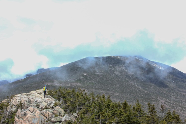 mountain and clouds with person in background on rocky summit
