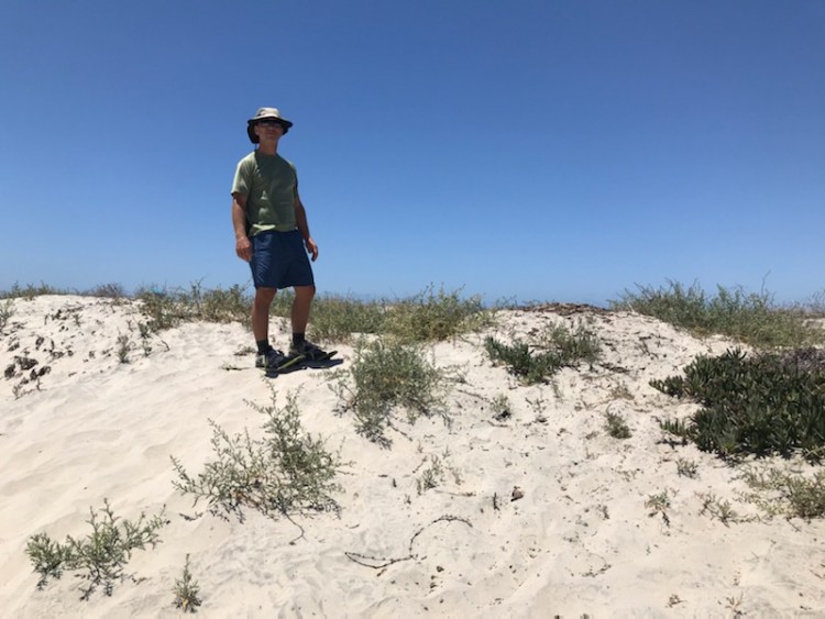 man on snowshoes standing on dune near beach