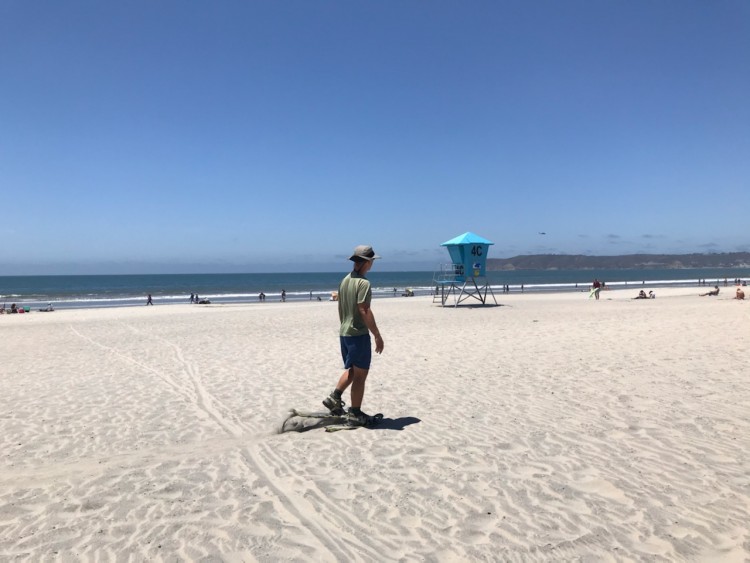 man using snowshoes on a beach with tower in background