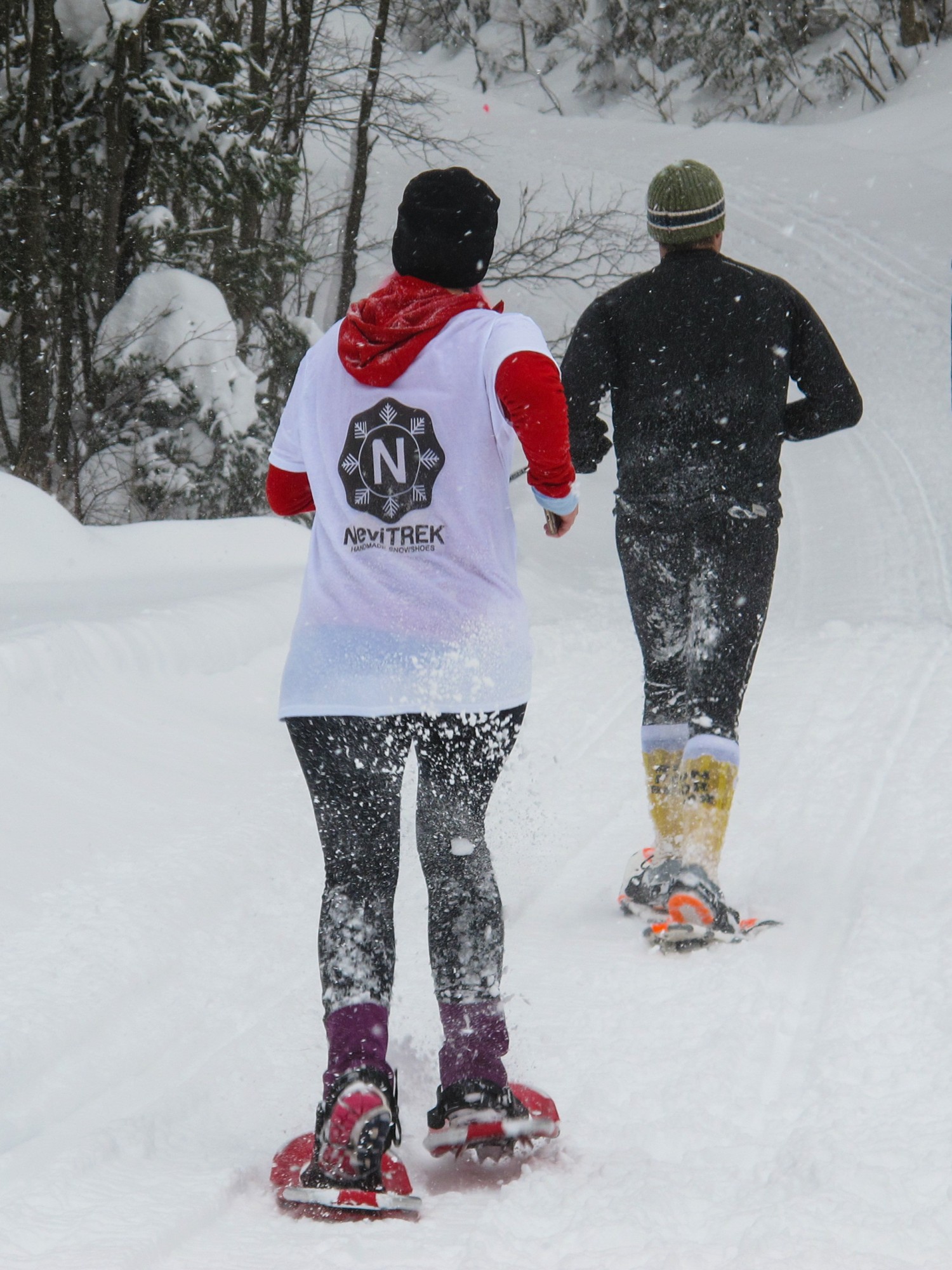 two people running in the snow with snowshoes