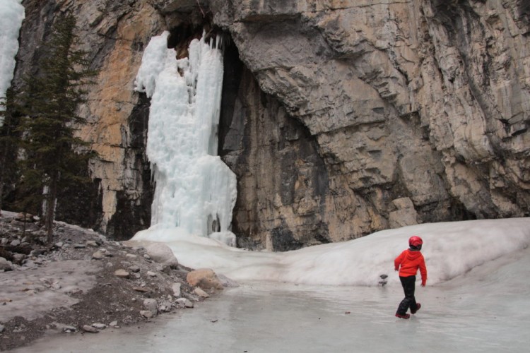child walking on ice near waterfall at Grotto Canyon, Canmore