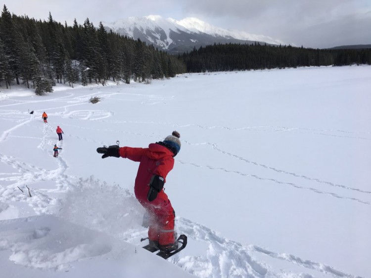 child jumping off hill on snowshoes