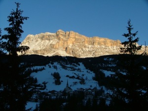 The first rays of the day's sun on Santa Croce Rock behind Badia