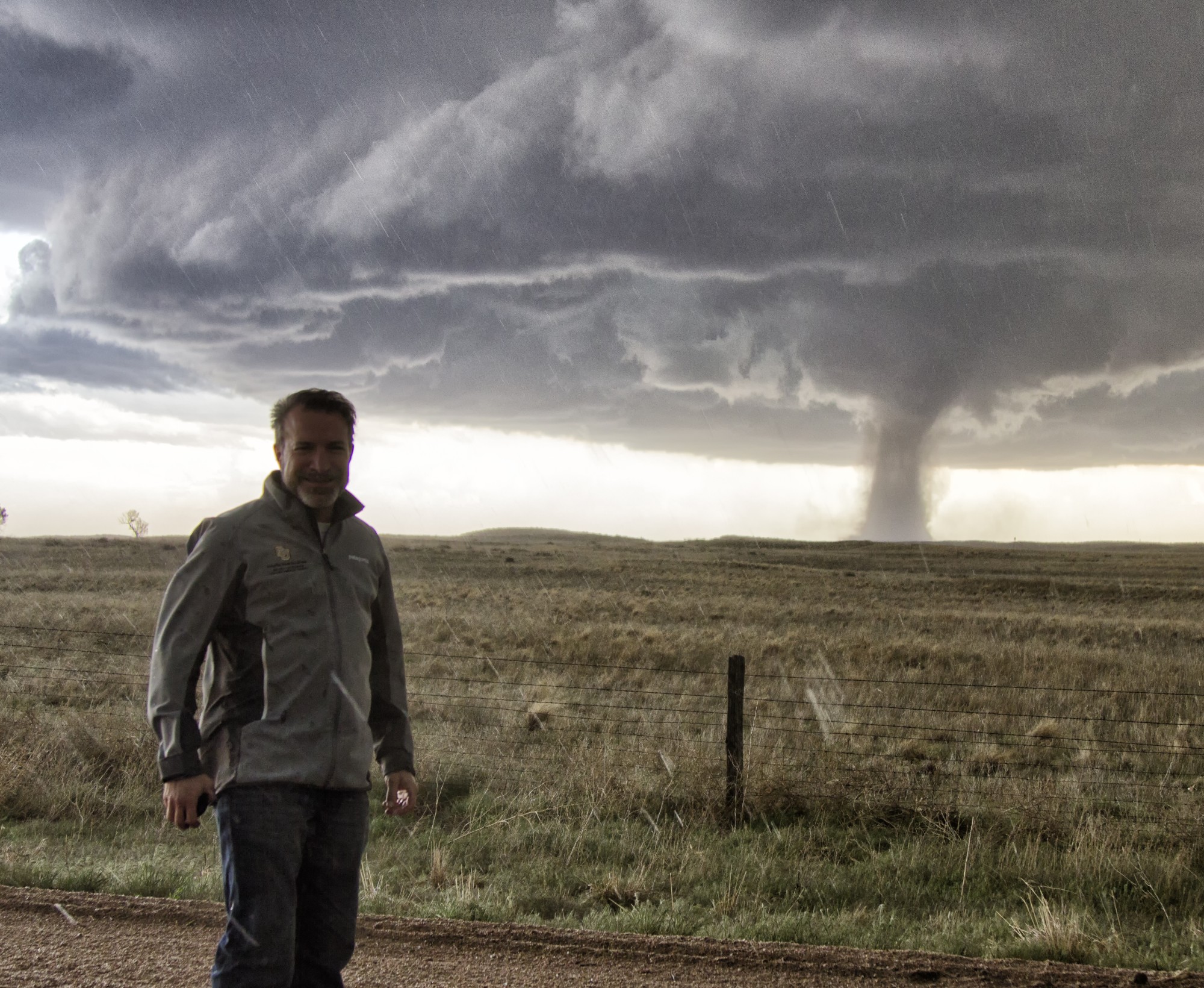 man standing in front of a storm funnel