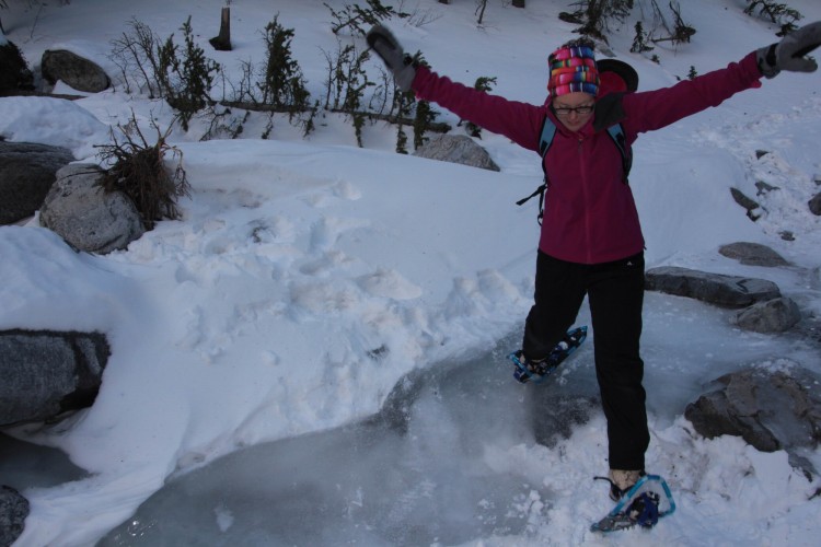 woman jumping across icy water in CM Gold 13 snowshoes