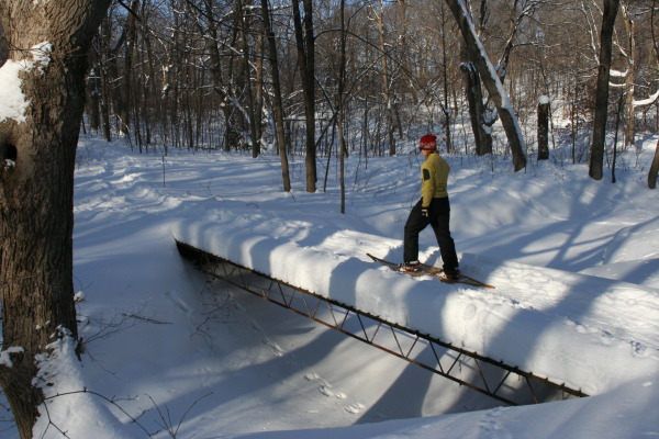 snowshoer walking on a bridge