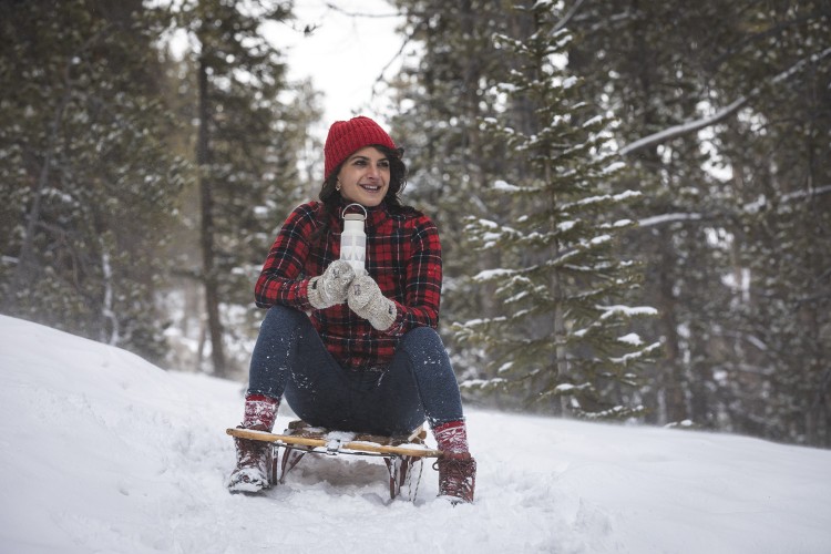 woman on sled in snow holding Klean Kanteen 12 oz vacuum insulated bottle