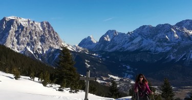 snowshoer next to cross on mountain summit