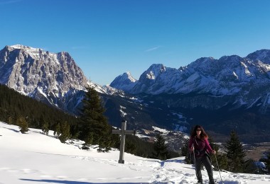 snowshoer next to cross on mountain summit