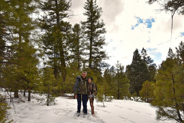 couple on snowshoes in front of trees under cloudy sky