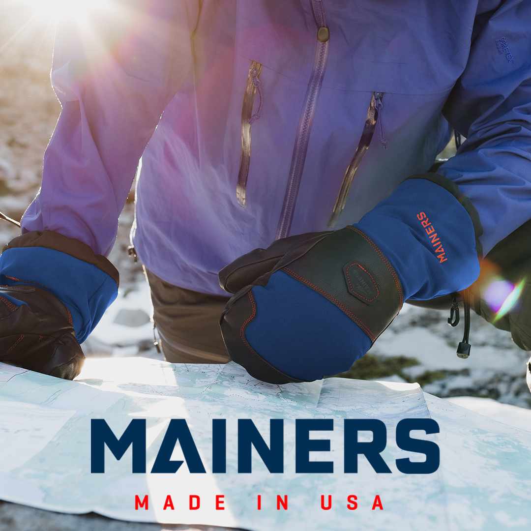 person wearing mittens with Mainers logo in the snow