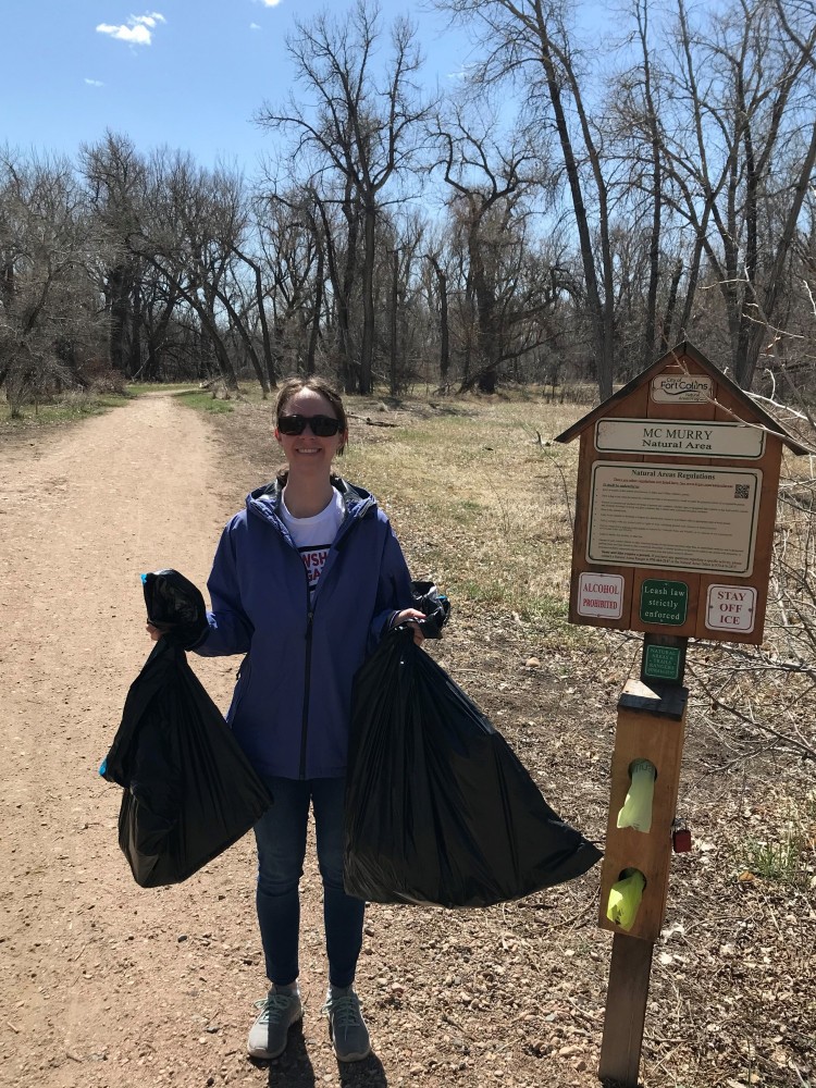 woman holding trash bags near natural area sign