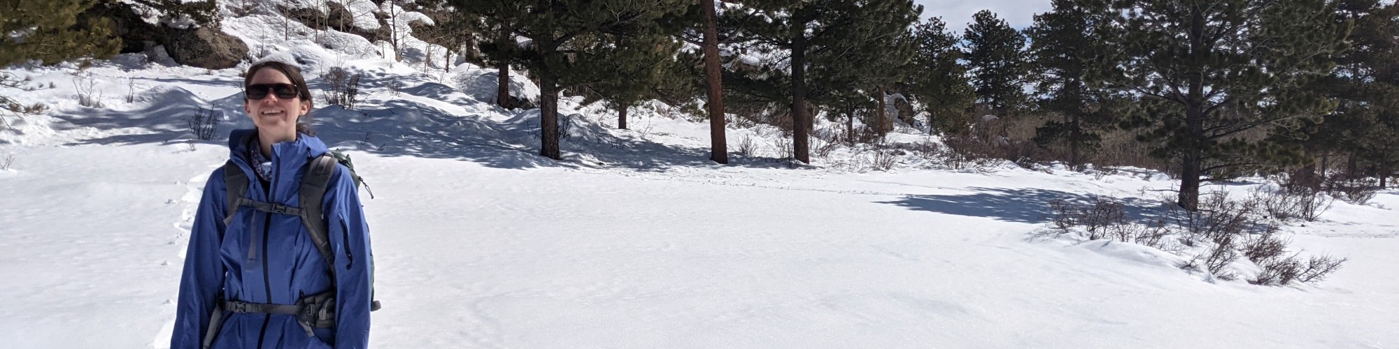 woman standing in the snow on snowshoes under blue sky