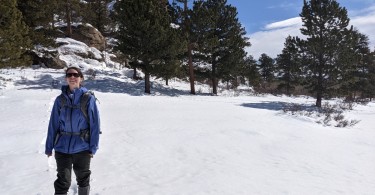 woman standing in the snow on snowshoes under blue sky