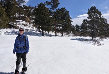 woman standing in the snow on snowshoes under blue sky