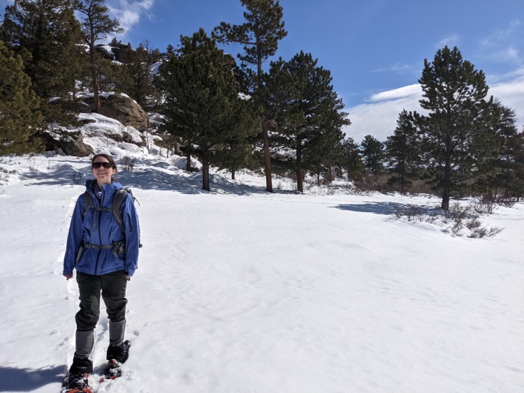 woman standing in the snow on snowshoes under blue sky