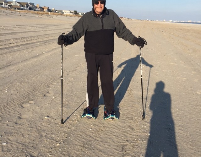 man posing with snowshoes and poles on sand